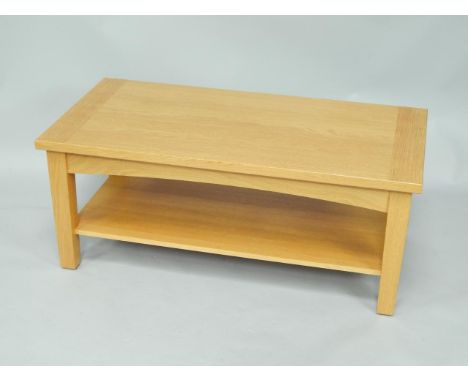 A light oak rectangular two tier occasional table, raised on square legs, 108cm x 55cm x 44cm.