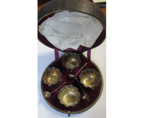 A boxed set of four silver salts, and matching spoons, with shaped edge and raised on ball feet, Birmingham 1883