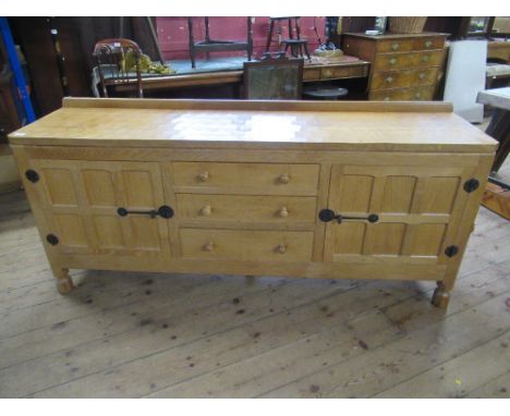 A Robert Thompson Mouseman oak side board, having adzed top, with three graduated central drawers with turned wooden handles,