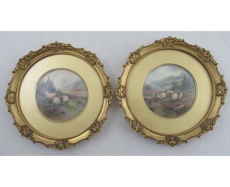 A pair of Royal Worcester circular framed plaques, finely painted with sheep in a landscape with spruce trees and water beyon