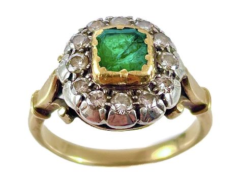 An early 20th century high purity gold emerald and diamond cluster ring. The cracked square cut emerald surrounded by twelve 