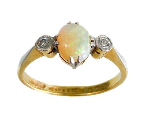 An early 20th century 18ct and platinum diamond and opal set three stone ring. The white oval opal displaying blue, green and