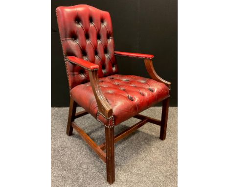 A mid 20th century button-back open arm office chair, sang de boeuf leather, mahogany arms and legs, 102cm tall. 