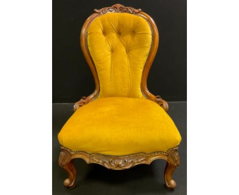 A Victorian upholstered walnut nursing chair, shaped  button back with carved cresting, carved side supports, seat front, and