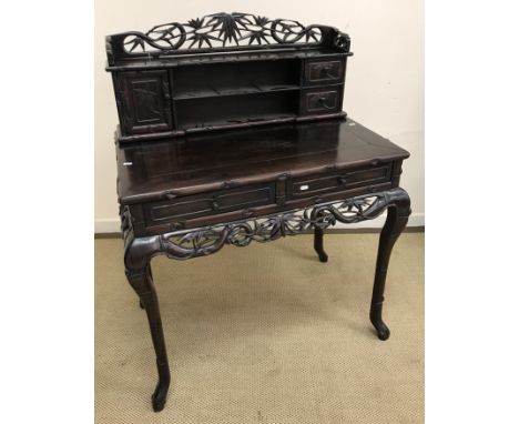 A 20th Century Chinese carved hardwood desk, or writing table, the shelved superstructure with two drawers and cupboard door,