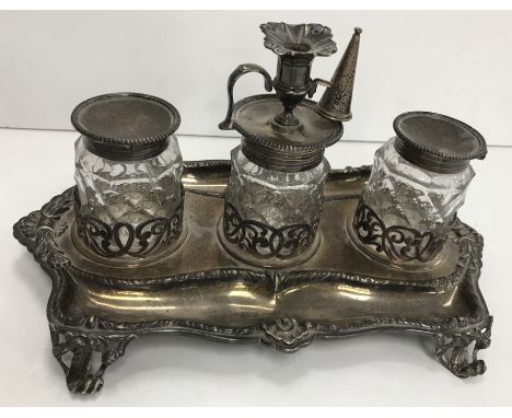 A Victorian silver desk stand with three facet cut lidded jars, the centre of which with chamber stick style wax burner on a 