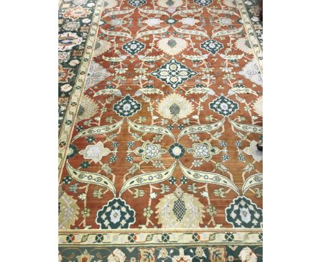 An Oriental carpet, the central panel set with scrolling foliate decoration on an orange ground, within a mustard, green and 