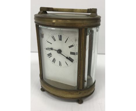 A circa 1900 French brass cased mantel clock of oval form, the enamelled dial with Roman numerals, 9 cm wide x 12 cm high