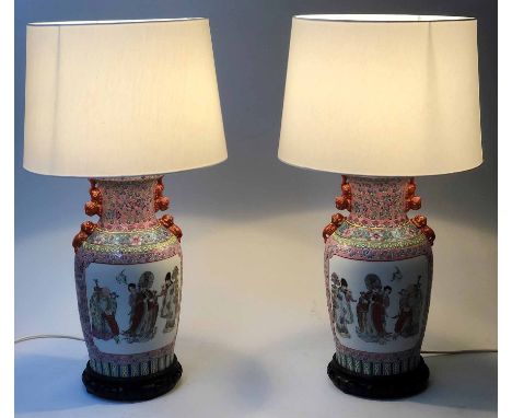 LAMPS, a pair, Chinese ceramic, figures in white panels and pink and green foliate ground on pierced wooden stands, 54cm H. (