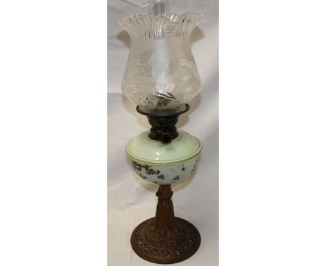 A Victorian oil lamp with ornate cast iron base, opaque glass floral decorated reservoir and frosted glass floral shade 