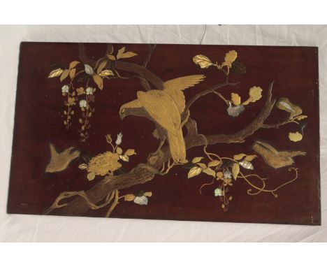 A Japanese lacquered mahogany rectangular panel depicting an eagle and birds amongst  flowers, heightened  with bone and moth
