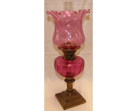 A good quality brass oil lamp with cranberry tinted glass reservoir and shade  