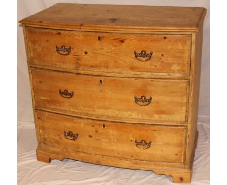 A polished pine bow-front chest of three short drawers with brass ring handles on bracket feet, 35" high x 37" wide 