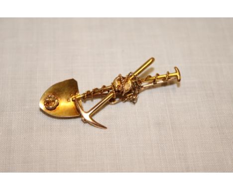 An unmarked gold miner's brooch in the form of a crossed pick and shovel with nugget decoration (4.5g)