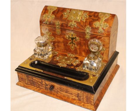 A Victorian brass mounted walnut and ebonised desk stand with letter rack enclosed by a hinged domed cover above a pair of cu