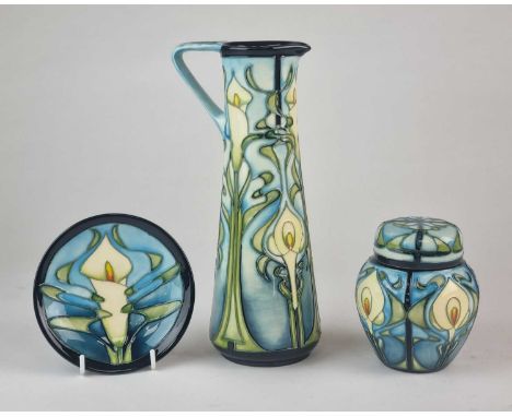 Three pieces of Moorcroft in the 'Calla Lily' pattern, comprising a jug, 23.7cm high; a small ginger jar and cover, 11.5cm hi