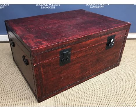 A modern Chinese red lacquered trunk with metal lock plates and side carrying handles 92 cm wide x 68 cm deep x 45 cm high (t