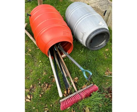 Two plastic water butts, one containing a collection of garden tools to include spade, long-handled edgers, etc