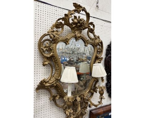 A 19th Century girandole mirror with scrolling foliate decoration around a shaped glass, the two light sconces with leaf deco