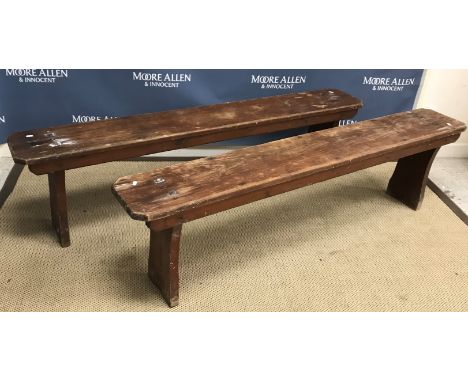 A pair of stained pine bench seats, the single piece tops on plank end supports 172 cm x 25 cm x 46 cm high