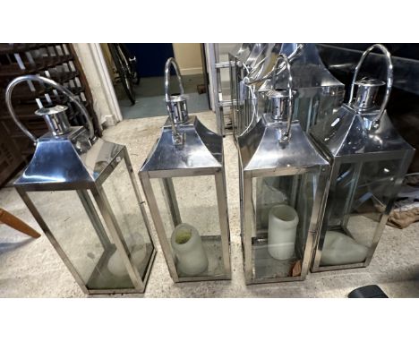 A collection of four modern metal framed four light exterior candle lights with swing handles, 76 cm high and a set of four t