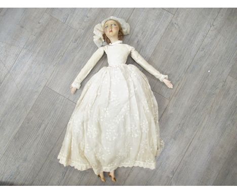 A straw filled doll with painted cloth face, ceramic hands and legs, in bridal dress and veil, approx 75cm tall 