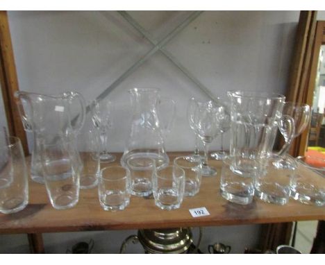 A shelf of glassware including 3 water jugs, glasses etc