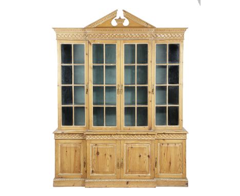 A PINE BREAKFRONT BOOKCASE IN GEORGE II STYLE 20TH CENTURY with an architectural pediment and Vetruvian scroll mouldings, the