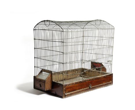 A BRASS WIREWORK BIRDCAGE EARLY 19TH CENTURY with a hinged door and mahogany base with two feeding troughs 52cm high, 62.5cm 