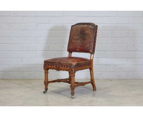 An oak dining chair, 19th century, the red leather upholstery with bold brass studs and gilt family crests, on a chamfered oa