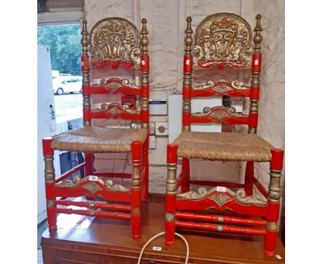 A pair of decorative painted wood and gilded ladder back armourial style standard chairs with woven rush seats, set on tuned 
