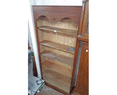 A 33 1/2" stained mixed wood six shelf open bookcase with shaped top apron and plinth base