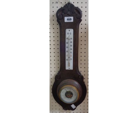 An early 20th Century oak backed wall barometer/thermometer with ceramic scale and visible aneroid works