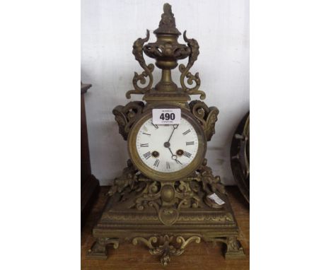 A late Victorian cast brass cased ornate mantel clock with urn to top and flanking masks with eight day French bell striking 