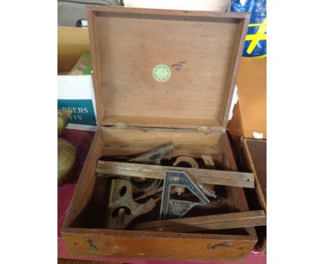 A wooden box containing a quantity of tools including micrometers, squares, etc.