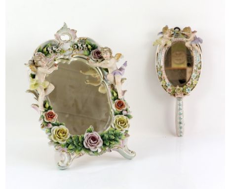 Dresden porcelain table mirror encrusted with flowers and foliage and mounted with winged cherubs, h31cm, and a similar hand-