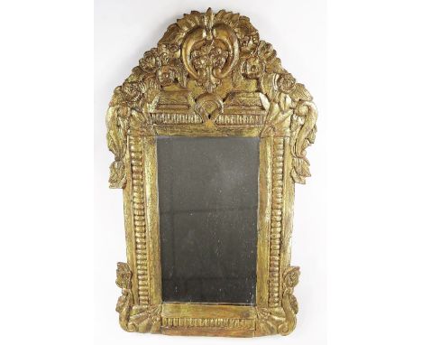 A heavily carved gilt wood mirror, the surround surmounted by scrolls and flowerheads with further scrolls to the sides, with