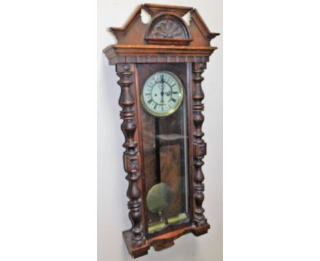 A late 19thC walnut cased Vienna wall clock, the cornice with a carved shell and scroll motif, above a glazed case flanked by