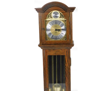 A 20thC oak cased granddaughter clock, the arched dial raised above a glazed door, on bracket feet,  with an arched 17cm Dia 