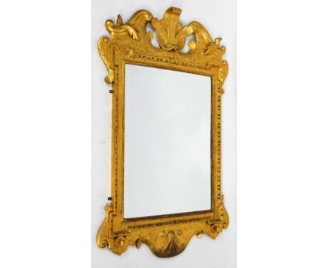 A gilt wood mirror, with Princes of Wales feather and scroll finial, above a bevel glass flanked by scroll sides with a shell
