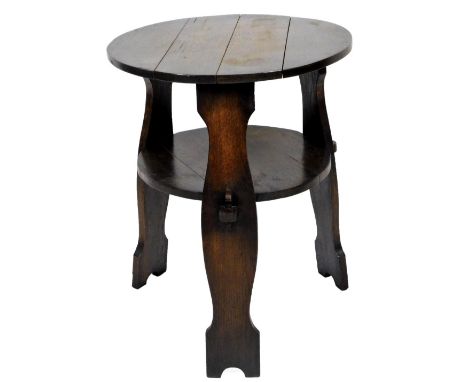 An Arts and Crafts type oak cricket table, the circular plank top raised above shaped stiles, joined by a shelf, 69cm H, 56cm