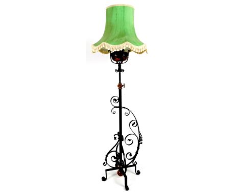 A wrought iron standard lamp, with cylindrical stem and scroll legs, with green shade, 145cm H.