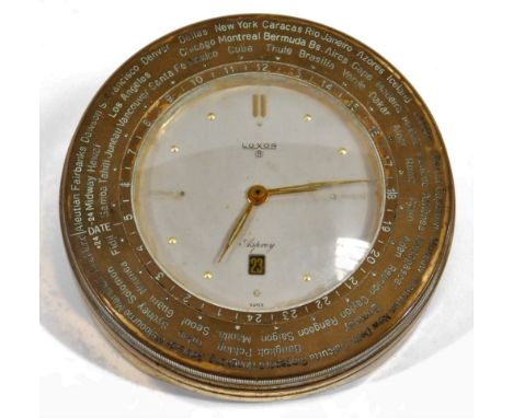 An Asprey Luxor World Time desk alarm clock, of circular form, with rotating brass bezel, 7cm Dia. dial with baton and line n