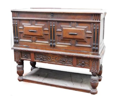 A 19thC continental oak side cabinet, the heavily carved front with inverted panelled fall, raised above three drawers, on he