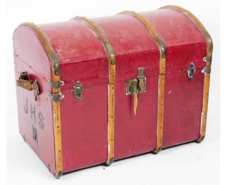 An early 20thC dome topped travel trunk, in pressed red leather, with wooden banding, partially studded, flanked by leather h