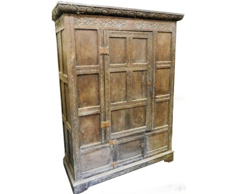 A 19thC oak hall wardrobe, with carved fixed cornice raised above a carved frieze and single door with panelled sides on brac