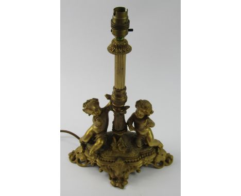 A gilt metal table lamp, cast with putti on a naturalistic and rococo foliate scroll base, 37cm high.