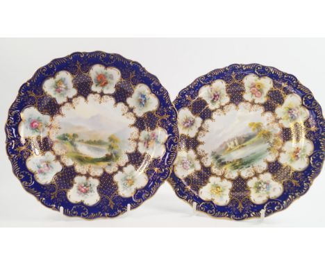 A pair of Royal Worcester porcelain plates, painted centrally with Scottish landscapes circa 1902, with border reserves of fl