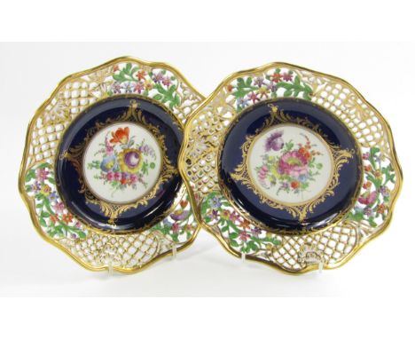 A pair of Meissen porcelain plates painted with flowers, against a cobalt blue and gilt foliate ground, within a pierced and 