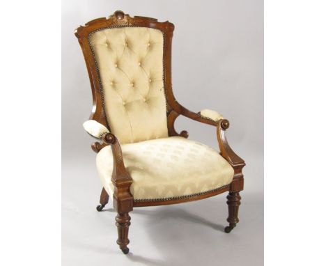 A Victorian mahogany armchair with carved crest rail, button back patterned fabric with overstuffed seat, scrolling arms, rai